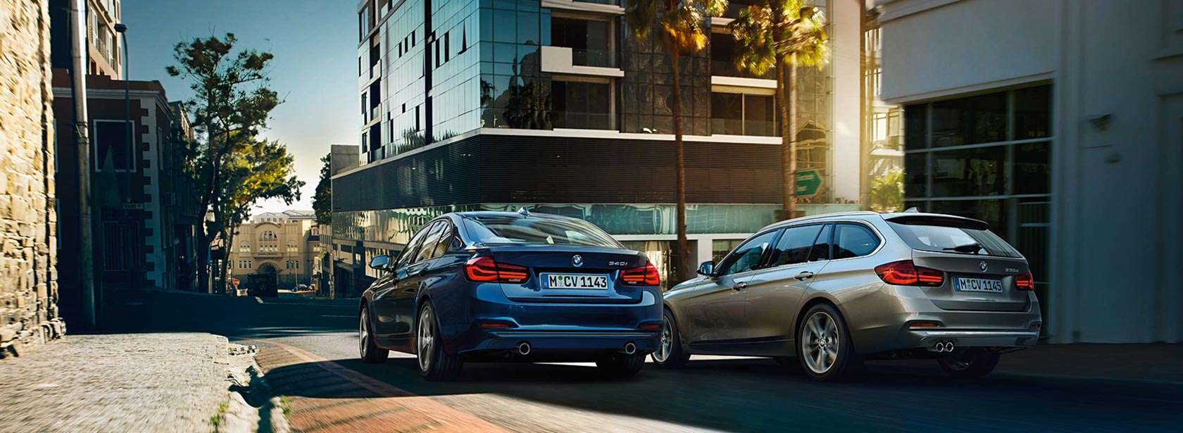 Aktualne oferty BMW zawsze zawiera ciekawe okazje. Dwa samochody BMW w przestrzeni miejskiej.